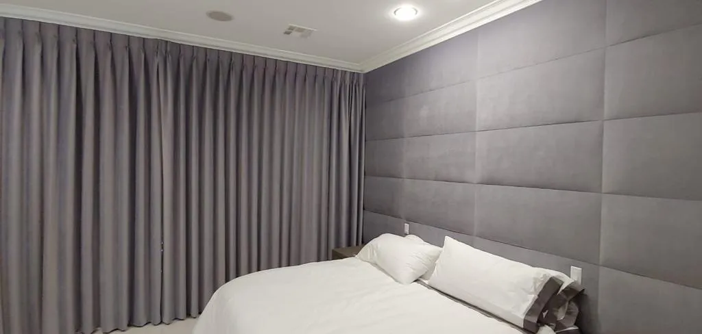 Bedroom with a floor-to-ceiling upholstered wall and drapery